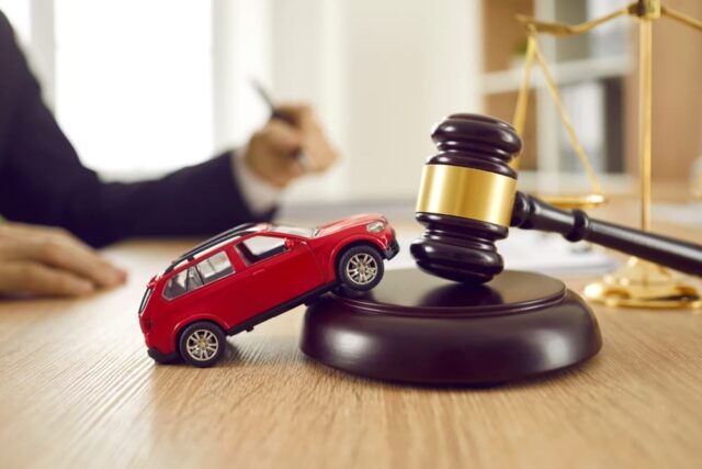 Houston Intersection Accident Case A small red toy car sits on a wooden desk alongside a judge's gavel and sound block, symbolizing a car accident case in a legal setting.