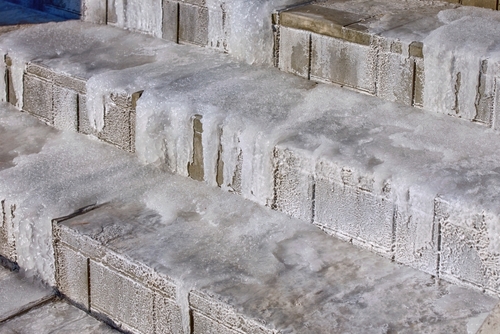 Ice-covered concrete stairs with visible frost buildup, creating a slipping hazard in winter conditions.