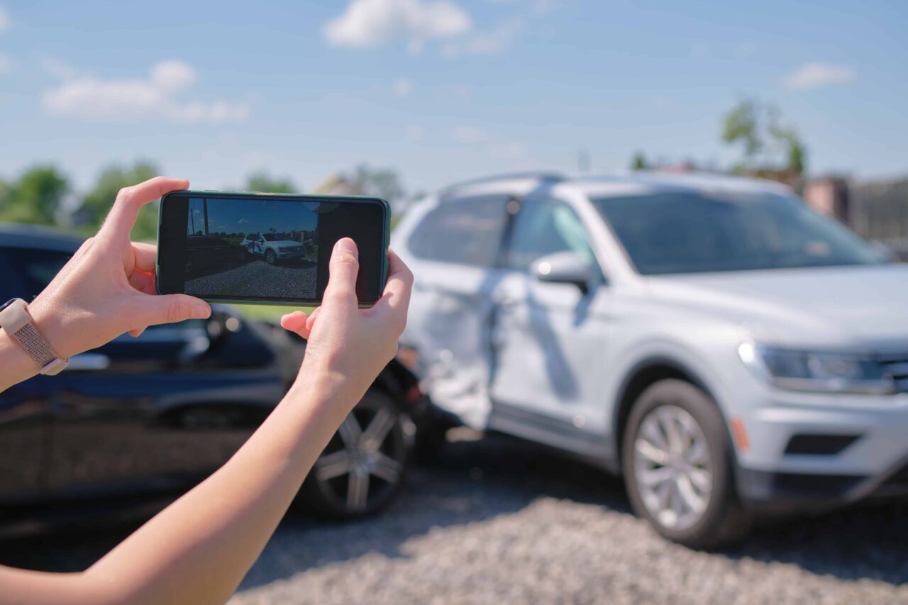 Person taking photos of a car accident scene for insurance claim documentation. Person taking photos of a car accident scene for insurance claim documentation.