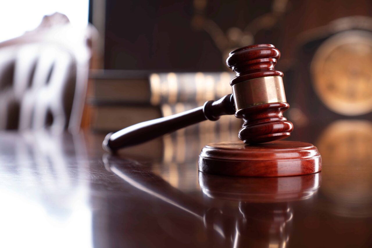 Judge’s wooden gavel resting on sound block in courtroom symbolizing justice and legal proceedings. Judge’s wooden gavel resting on sound block in courtroom symbolizing justice and legal proceedings.
