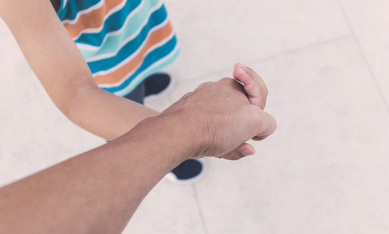 Close up of a parent holding a child’s hand, concept image representing protecting a minor’s car accident settlement in Texas