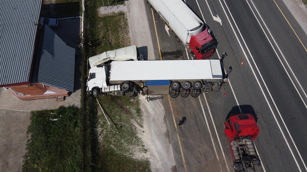 Aerial view of a truck accident with a jackknifed trailer near a roadway building