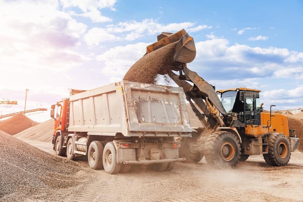 Loader filling a dump truck bed with material at a job site